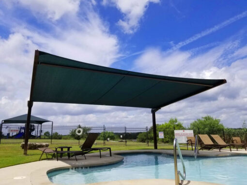 Green cantilever shade structure over a community pool deck