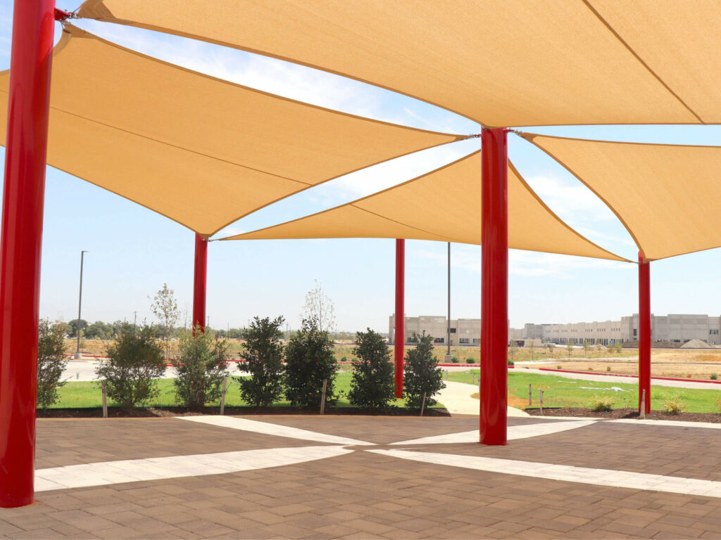 Overlapping triangle shade sails on steel posts layered over a paved patio, showing combined shade sail coverage