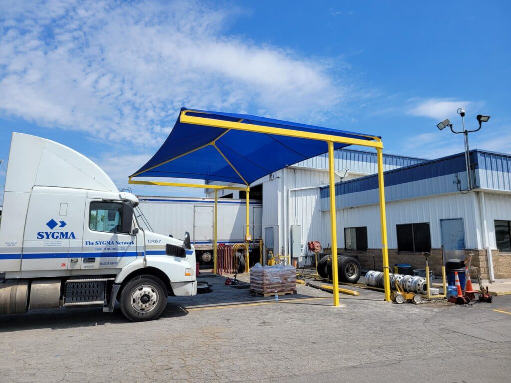 Commercial shade sail installation over parking lot using custom orange canopy structures for sun protection and curb appeal.