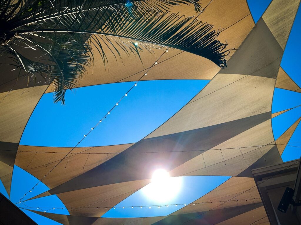 Triangular shade sails over a sunny patio—residential shade installation by a local shade provider.