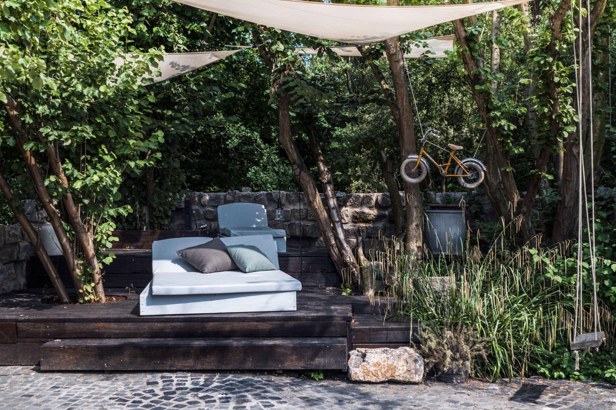 Modern garden shade structure with lounge seating under trees, creating a cool, relaxing space for Texas homeowners.