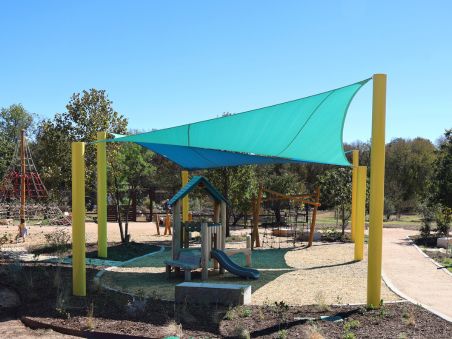 Cantilever outdoor shade structure over bleacher seating at a sports facility