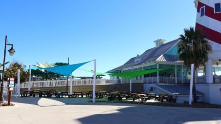 Outdoor shade structure with fabric canopies installed over a fenced entry area
