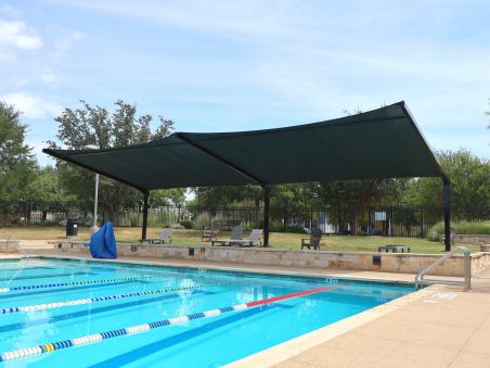 Umbrella-style outdoor shade structure installed beside a swimming pool